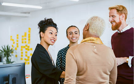 Colleagues standing in a small group discussing something while working at an office 