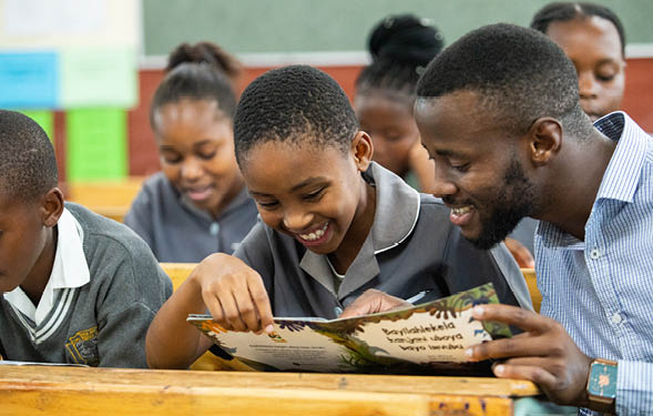 Mbutho Siphile (Grade 5), reading in class with teacher Mr T. Mrya, following the UNICEF-managed REALS SA (The Reading and Leadership Strengthening in South African Schools for Learning) reading programme which is in aid to support the DBE (Department of Basic Education) in managing the impact of COVID-19 in Tholisu Primary, Umlazi township in KwaZulu-Natal, South Africa. 05 Dec 2022. UNICEF. S.Moultrie (Slingshot Media) 